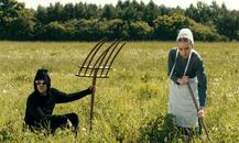 man holding pitch fork, woman gardening in field