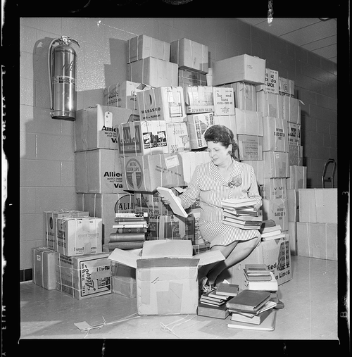 A picture of Doris Lewis unpacking Lady Aberdeen Memorial Library collection boxes, 1966. Kitchener-Waterloo Record.