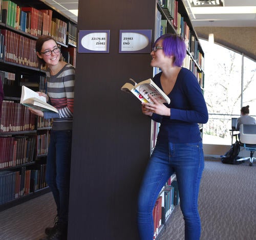 two women standing with books