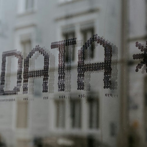 the words data in a digital font on a window with a building reflection in the background
