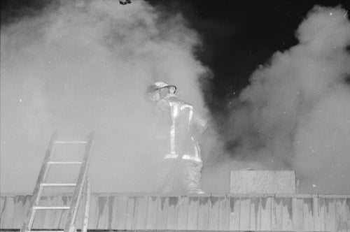 Fire fighter on roof with smoke