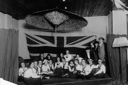 Women on stage in front of British flag.