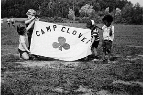 Children holding camp clover sign.