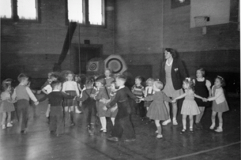 Group of children holding hands in gymnasium. 