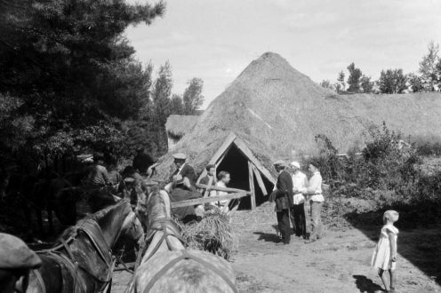 two horses and people in front of peasant home
