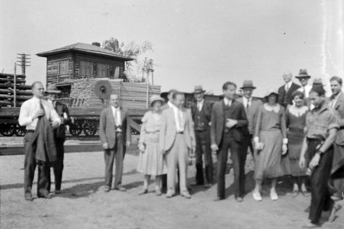 group photo, raw material transported on wagon in background