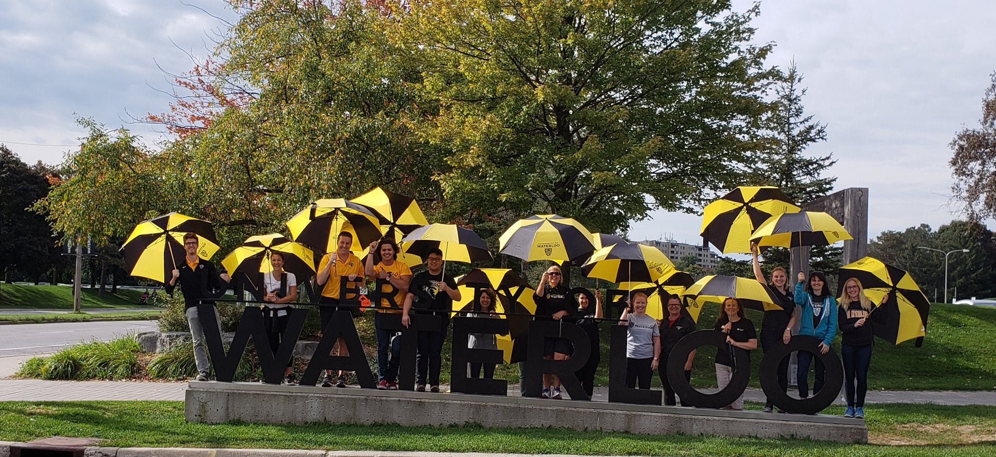 people holding umbrellas behind Waterloo sign
