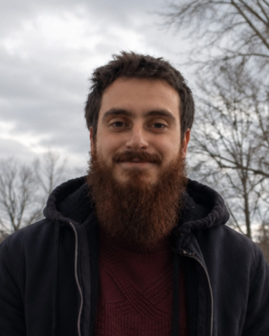 A headshot of Musa, who is outside on a cloudy day.