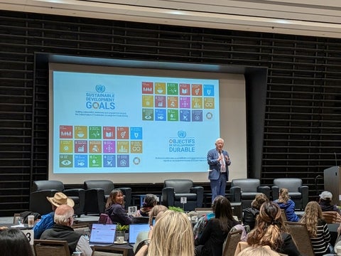 The Honorable Bob Rae speaking in front of an image of the SDGs.