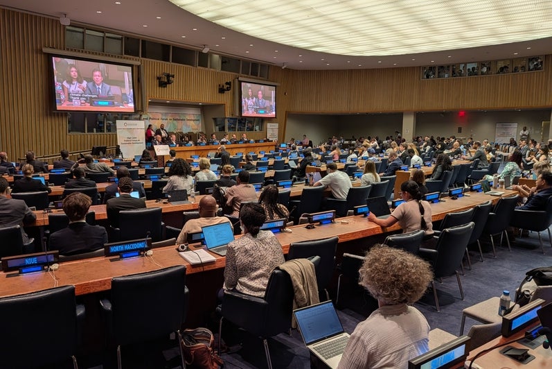 a room of people listening to a presentation at the UN