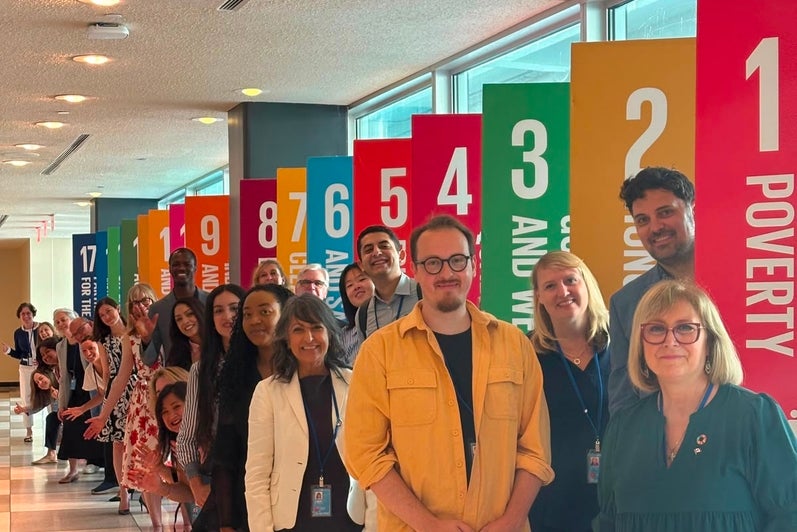 Canadian delegates standing in front of signage of the SDGs