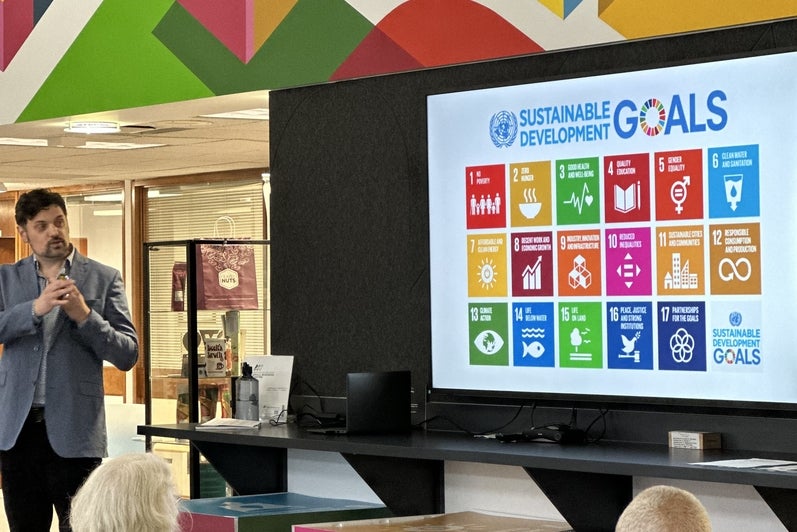 Jon Beale (Local Futures, Director) presenting in front of an image of the SDGs. 