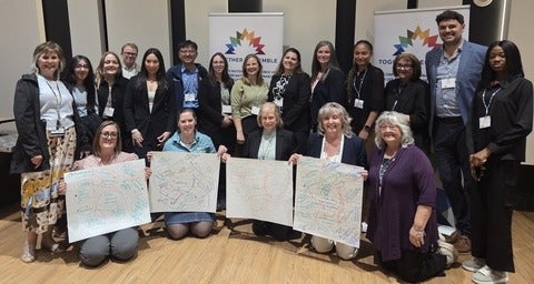 Group photo with people holding system maps from workshop activity