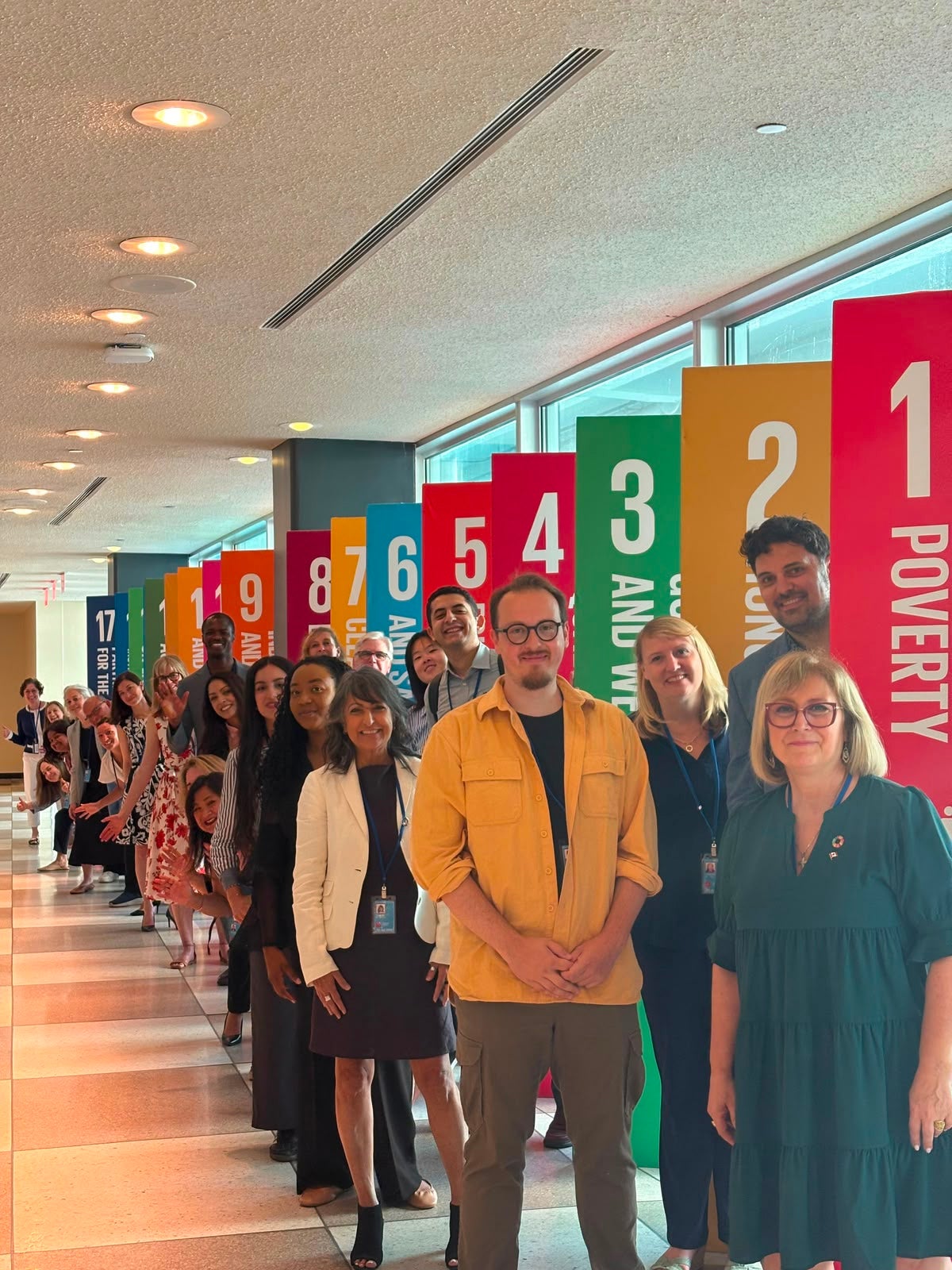 Canadian delegates standing in front of signage of the SDGs