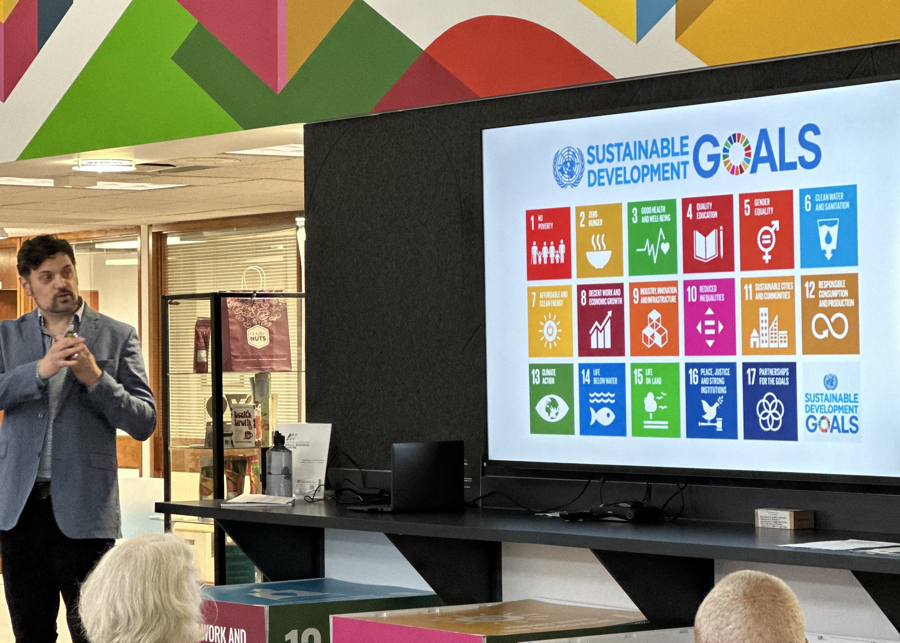 Jon Beale (Local Futures, Director) presenting in front of an image of the SDGs. 