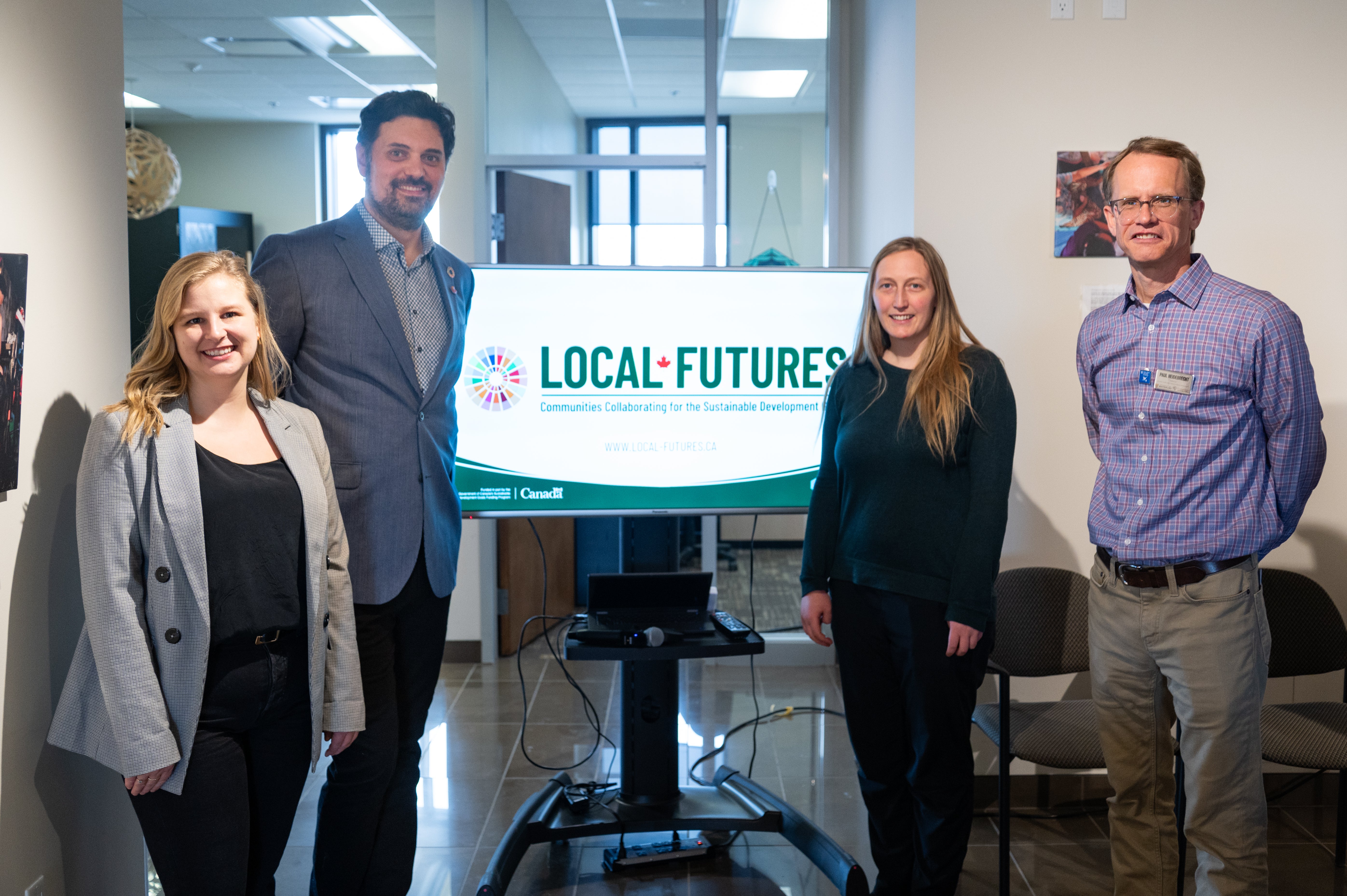 Local Futures team of 4 people posing for a photo next to the project brand