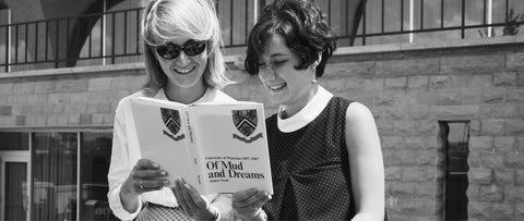 Black and white archival photo of two students looking at a brochure