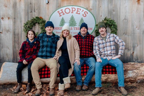 Group of people sitting on a log at Hope's Christmas Tree farm