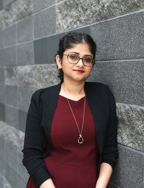 Prof. Sirisha's headshot. Background grey brick wall
