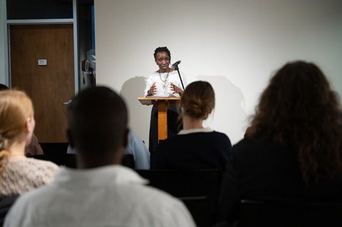A woman at a podium speaks to an audience passionately