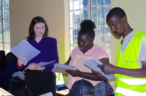 Student beside employees holding papers