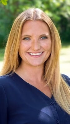 Kelly, with blonde long hair, wearing a blue shirt, smiling