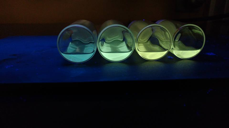Close up of vibrant blue, green, and yellow quantum dots under UV/black light