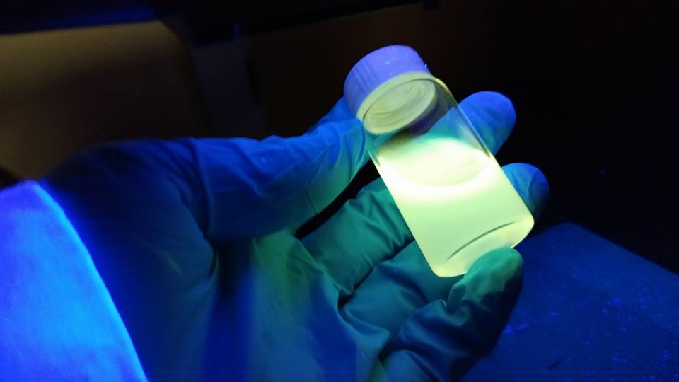 Students holding up quantum dots in gloved hand