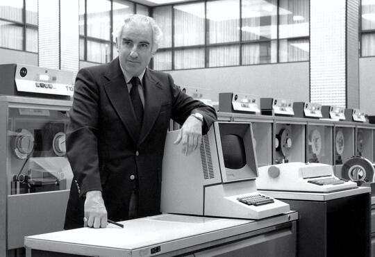 black and white photo of man surrounded by older computers