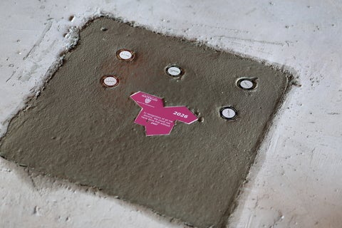 Einstein tile placed in wet concrete alongside Gillam coins.