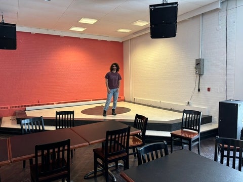 Damian Mikhail stands on the stage of the re-opened Bomber as it looks today