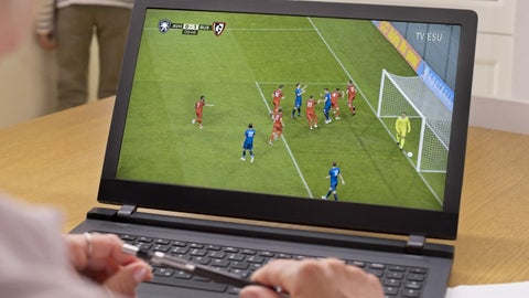 A laptop with a soccer game playing on it.
