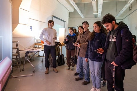 students gathered around a half circle holding their phones looking at a screen