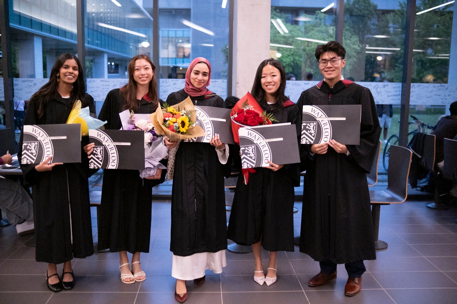 five people standing side by side holding diplomas