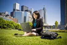 Woman working on computer in city park.