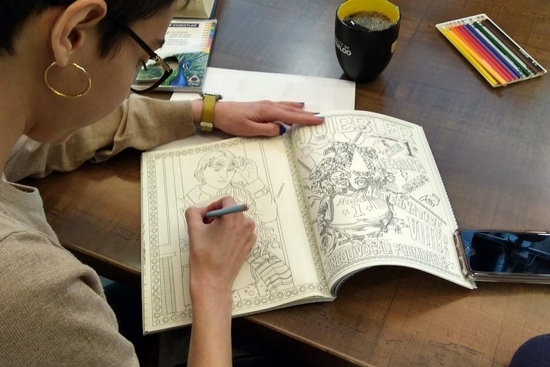 A student colouring in a picture in a colouring book.