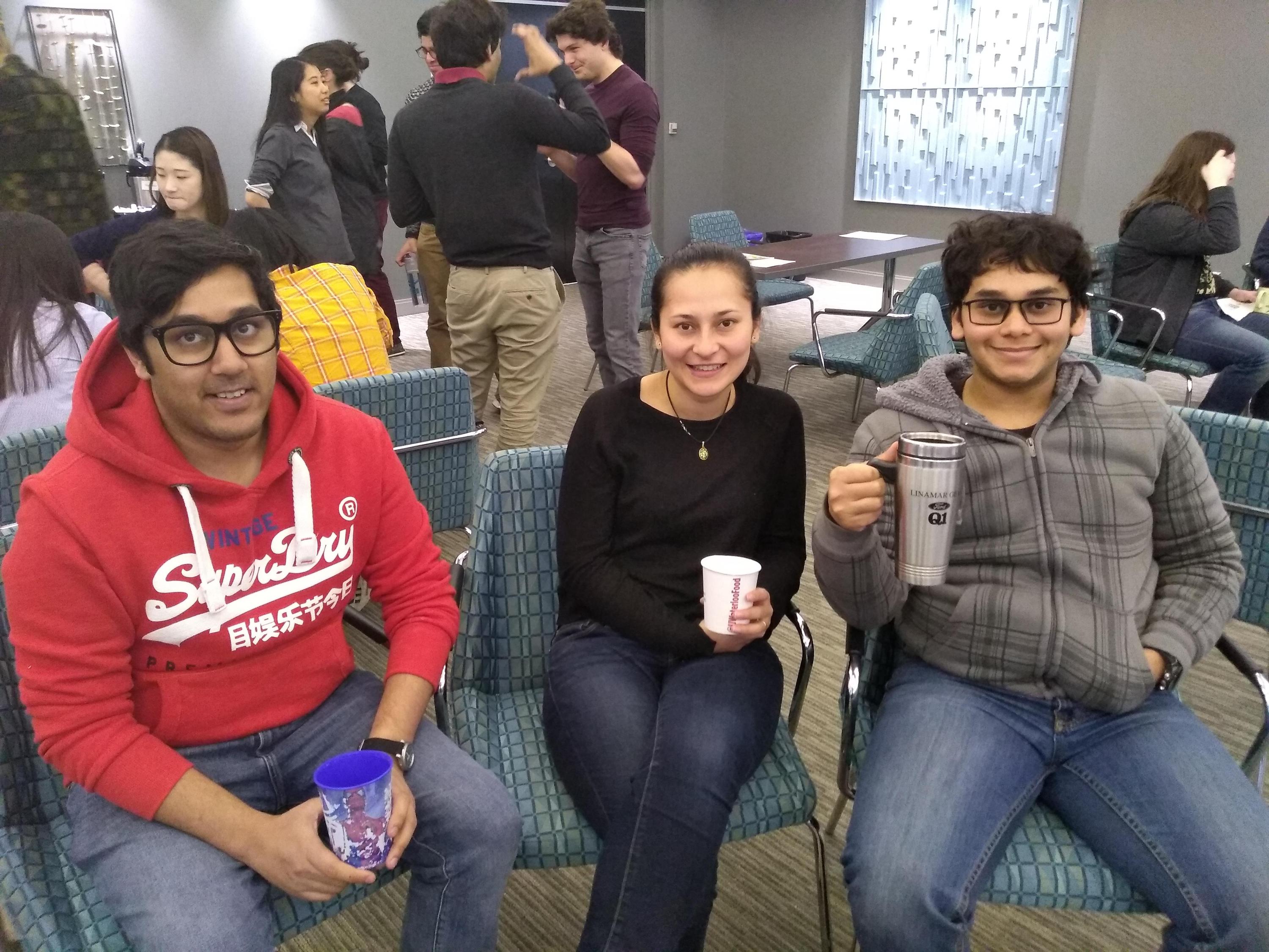 Three students sitting holding coffee cups