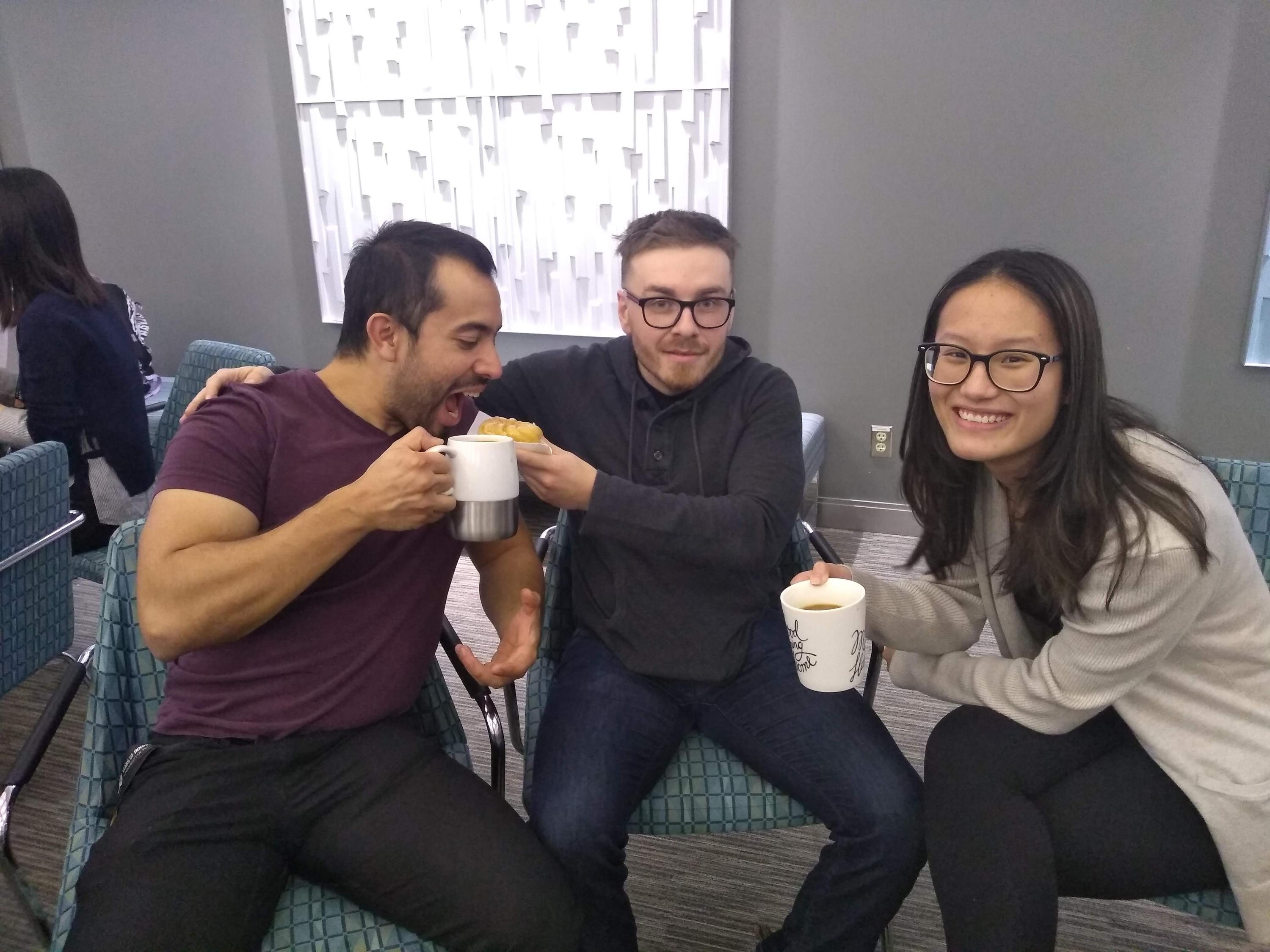 Three students sitting with coffee and donuts