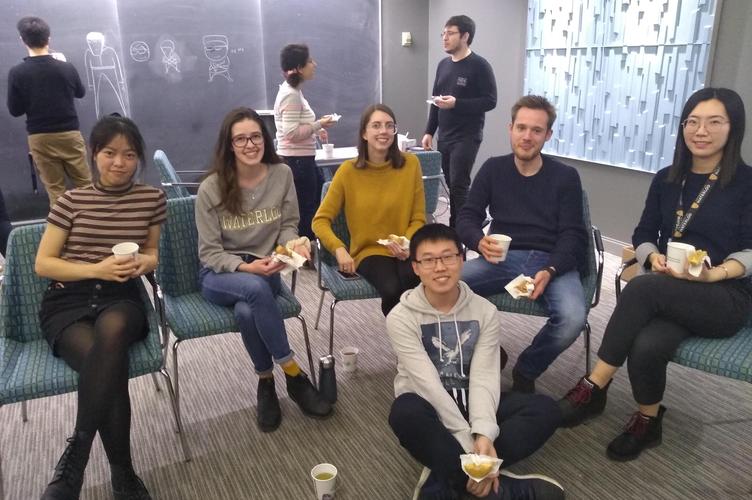 A group of students sitting in a classroom holding cups and donuts