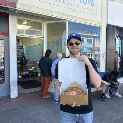 man standing with a pie outside of a bakery