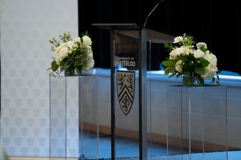 University of Waterloo branded podium with bouquet of flowers on each side