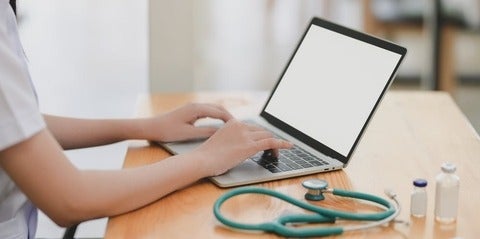 Physician typing on a laptop