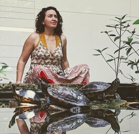 Adina Goldberg seated behind a pond with turtles