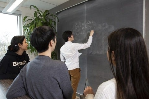 Statistics graduate students working at a blackboard