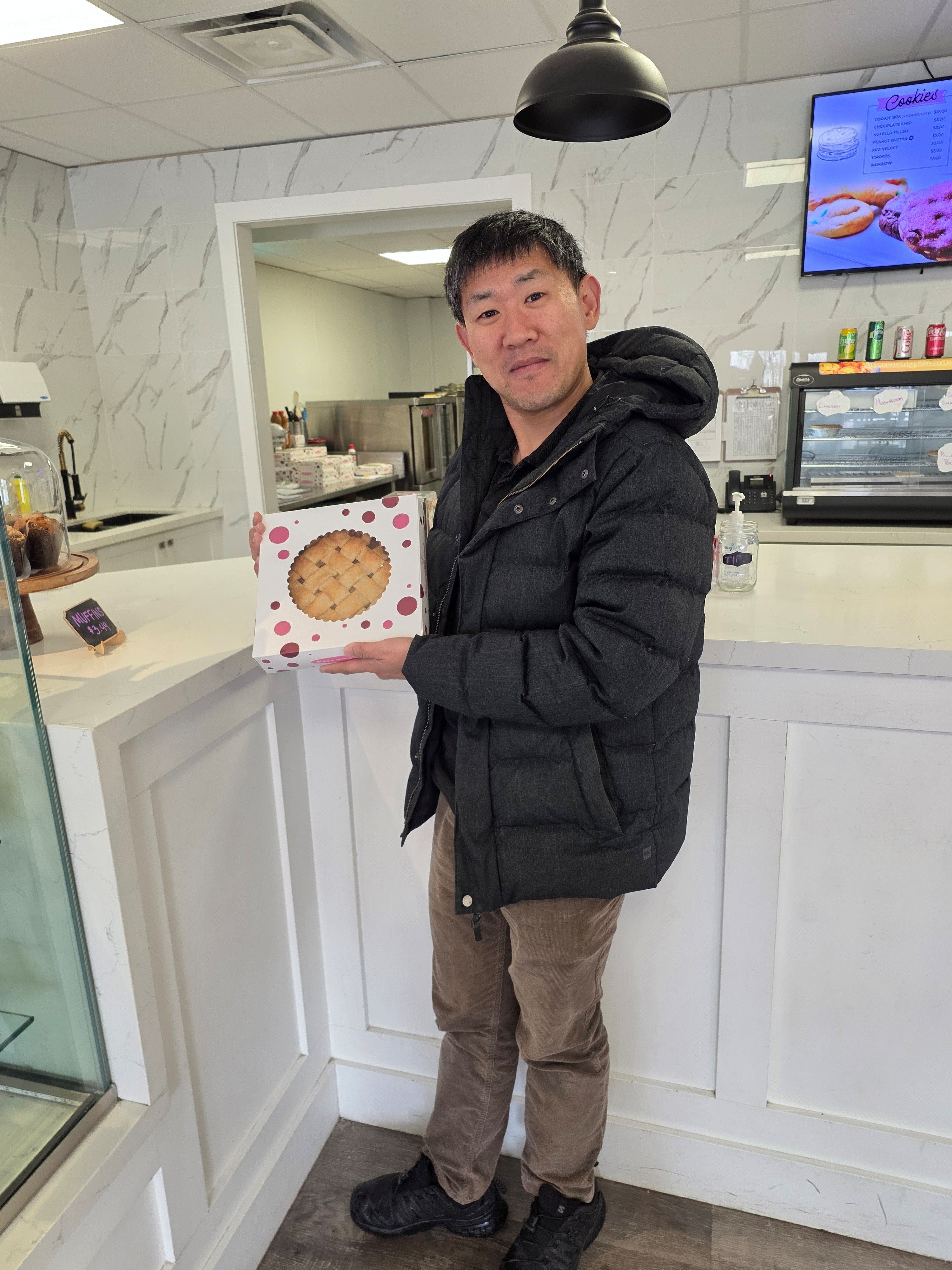 man standing and smiling holding a pie