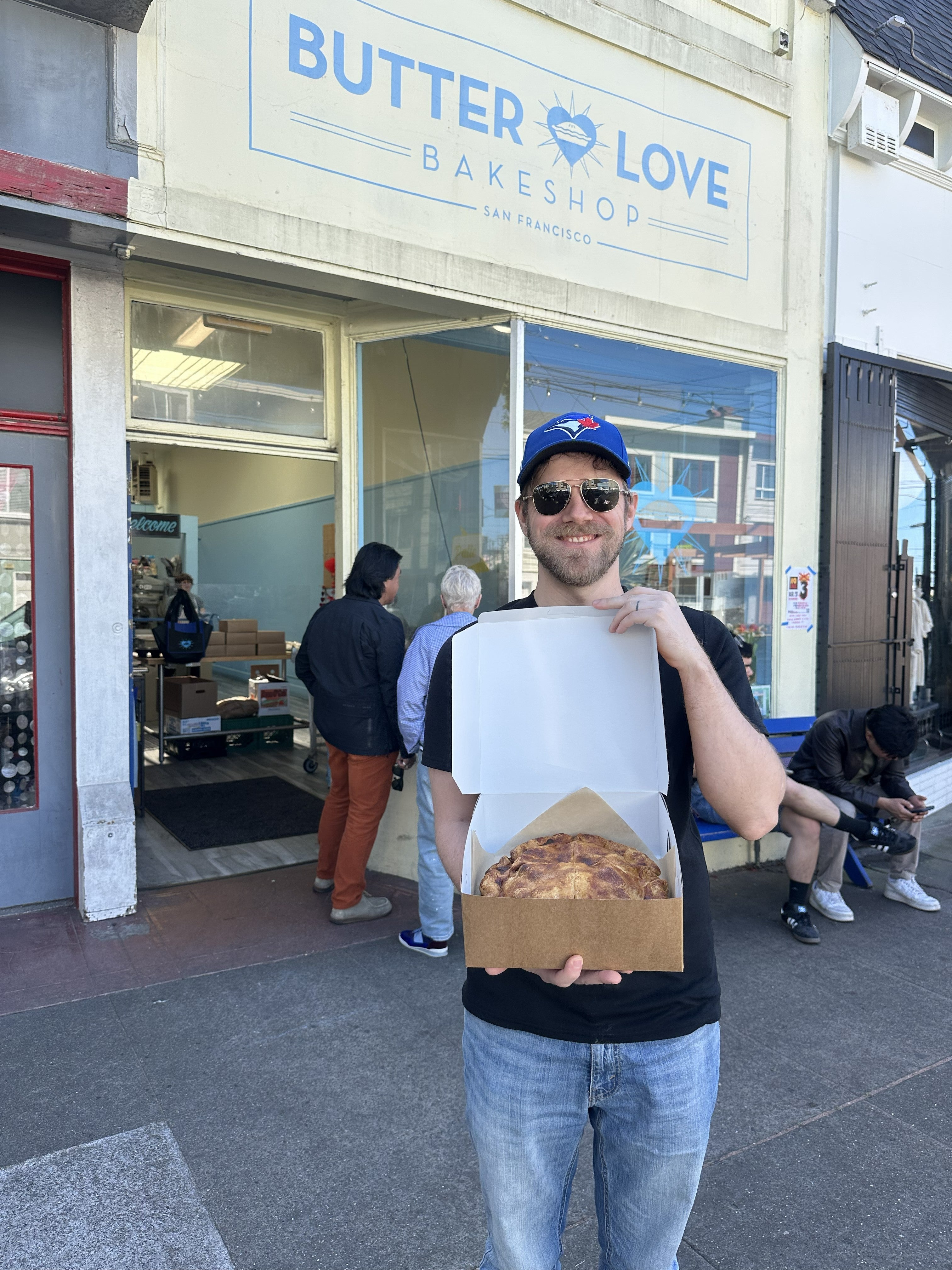 man standing with a pie outside of a bakery