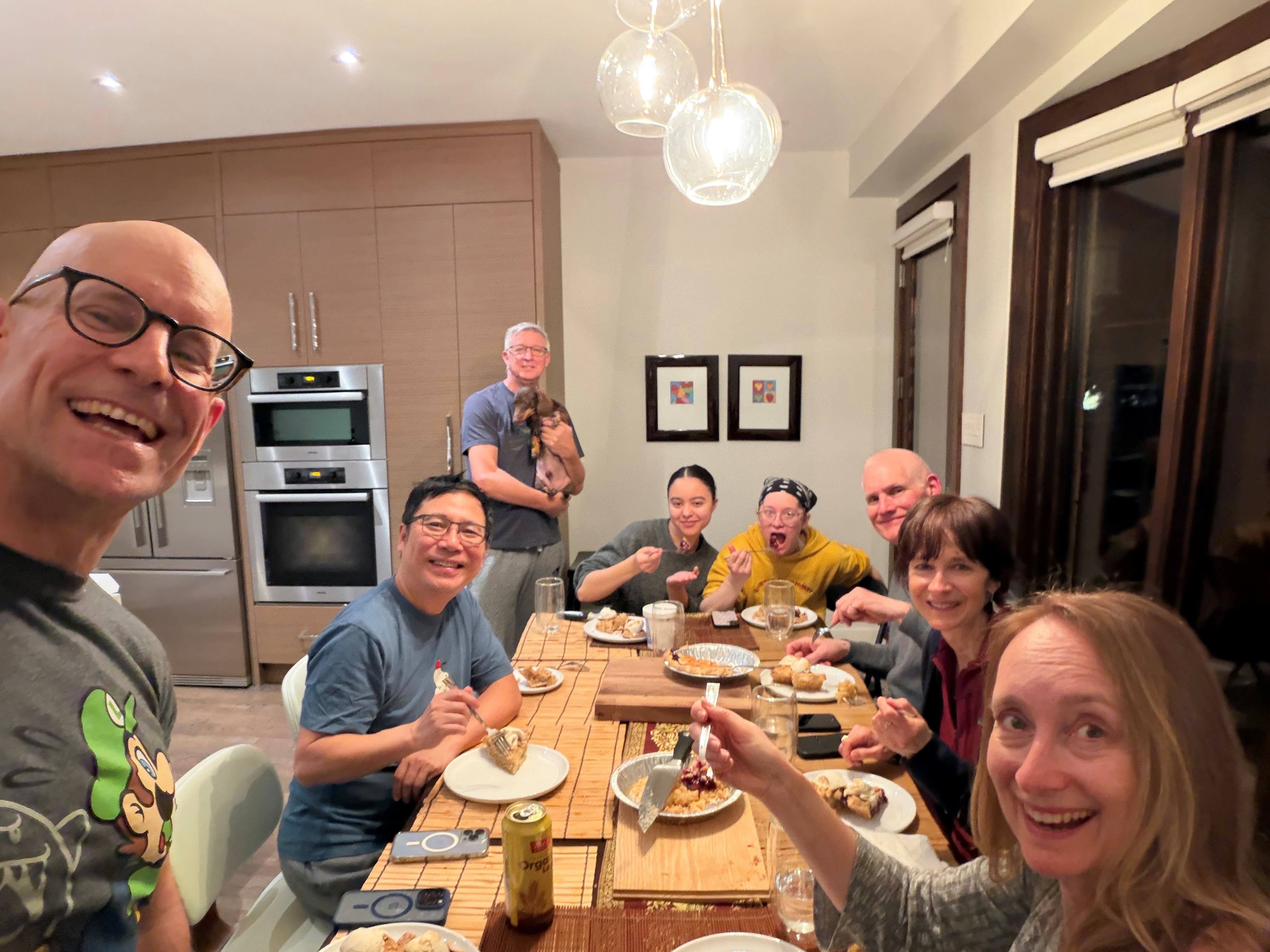 8 people sitting around a table eating pie