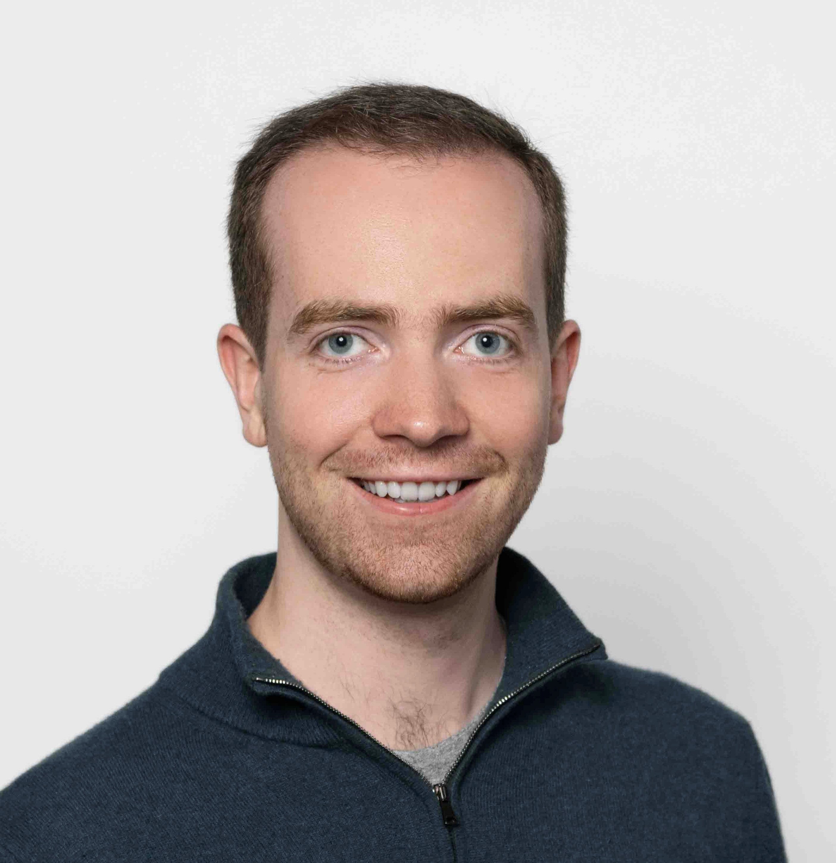 headshot of man smiling wearing a blue shirt