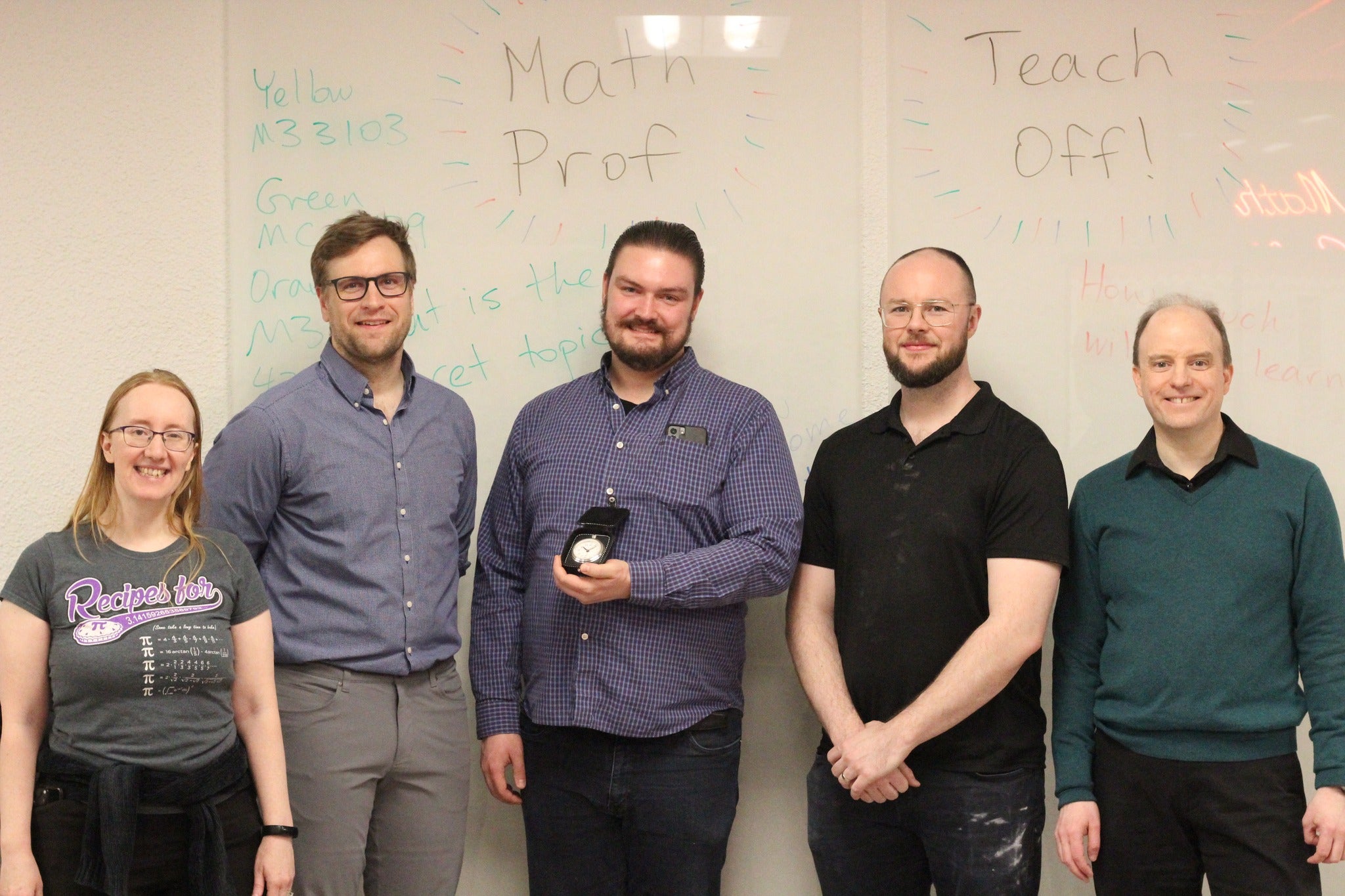 The three math instructors and two organizers stand in front of a whiteboard