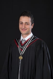 yougng man with dark hair wearing a graduation robe